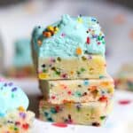 Three unicorn bars stacked with the top bar decorated with fluffy blue frosting and sprinkles.