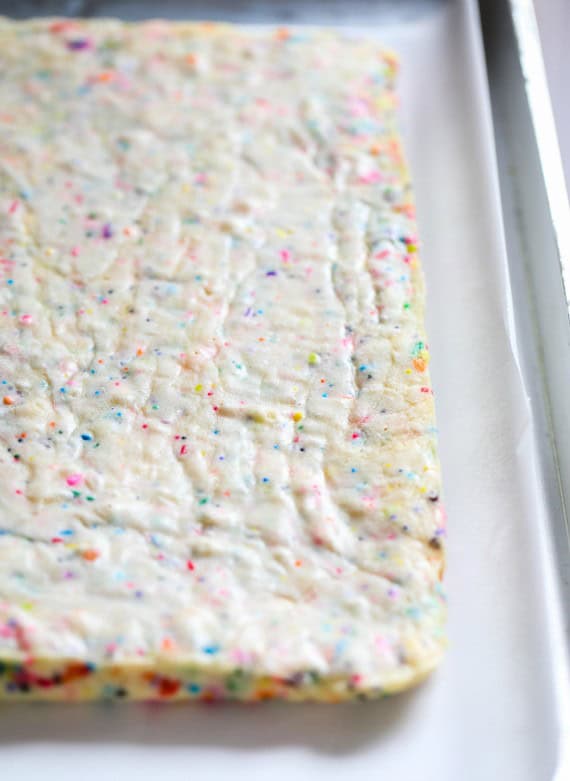 Unicorn bars are a fun, easy dessert! Buttery, soft-baked funfetti cookie bars loaded with rainbow sprinkles and frosted with homemade icing. Freshly baked unicorn bars that are just set and barely golden at the edges.