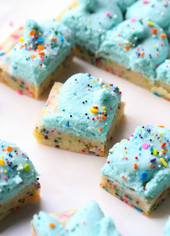 Unicorn bars are a fun, easy dessert! Buttery, soft-baked funfetti cookie bars loaded with rainbow sprinkles and frosted with homemade icing. Unicorn bars cut into squares, topped with creamy blue frosting and sprinkles.