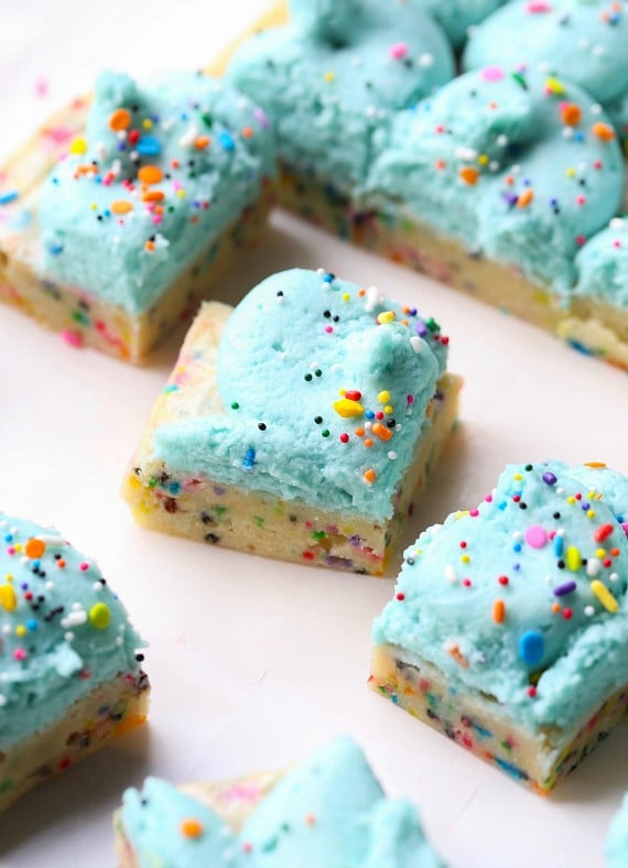 Unicorn Bars are buttery, sugar cookie bars loaded with rainbow sprinkles and topped with clouds of blue buttercream!