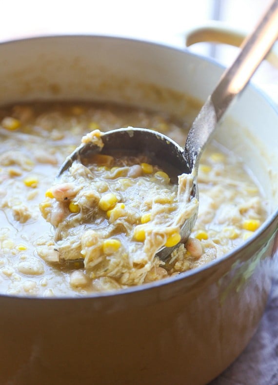 White chicken chili is ladled out of a Dutch oven.