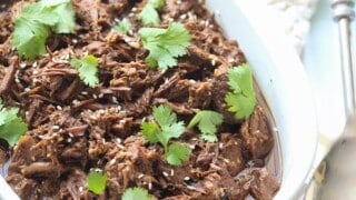 Korean beef topped with sesame seeds and cilantro in a ceramic serving dish.