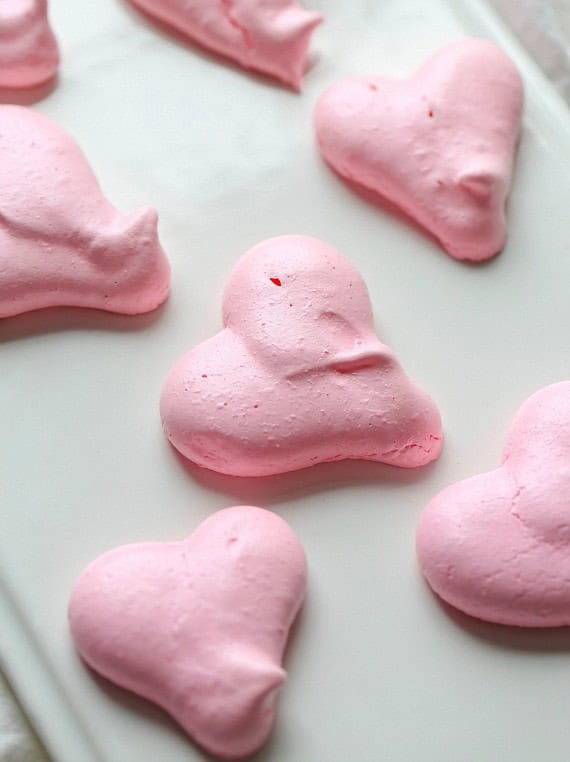 Heart Shaped Meringue Cookies on white parchment paper.