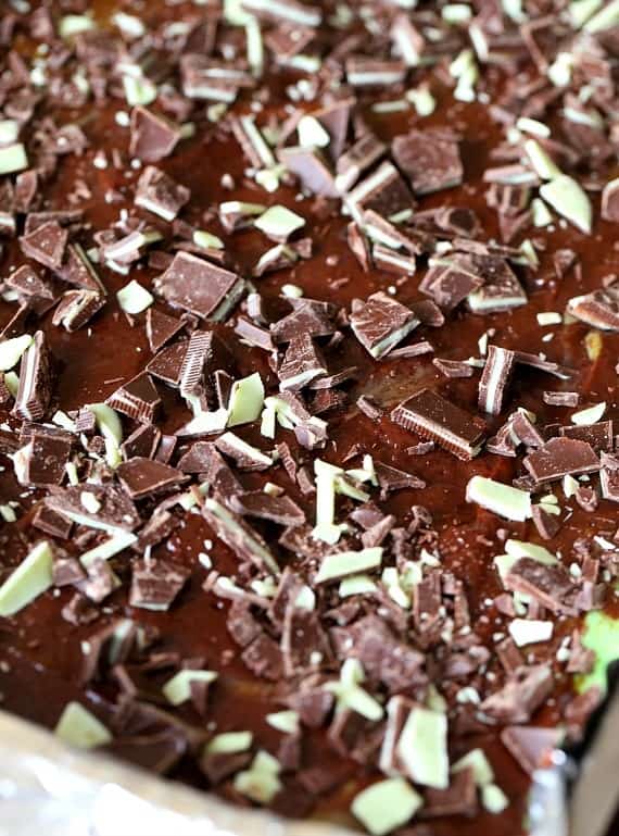 Close up of unbaked brownies topped with mint chocolate candy bars chopped into small pieces.