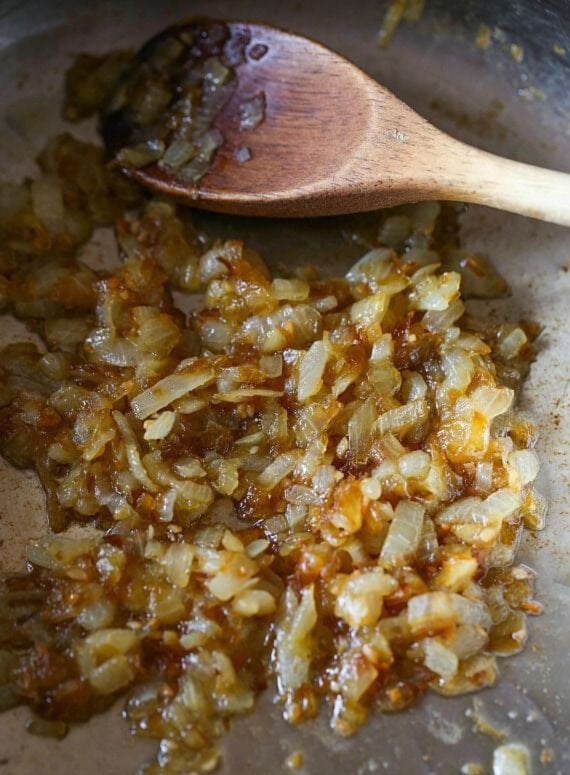 Caramelized onion in a skillet with a wooden spoon.
