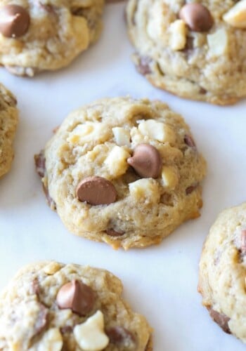 Homemade Sausalito cookies with chocolate chips and macadamia nuts on white parchment paper.