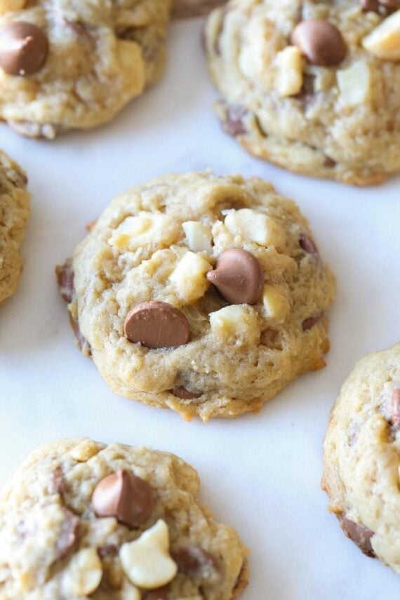 Homemade Sausalito cookies with chocolate chips and macadamia nuts on white parchment paper.