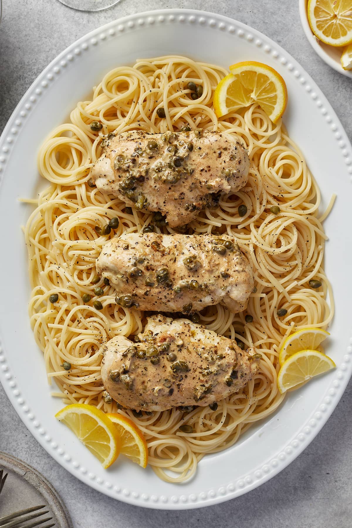 Chicken piccata pieces in lemon sauce served over a bed of spaghetti pasta.