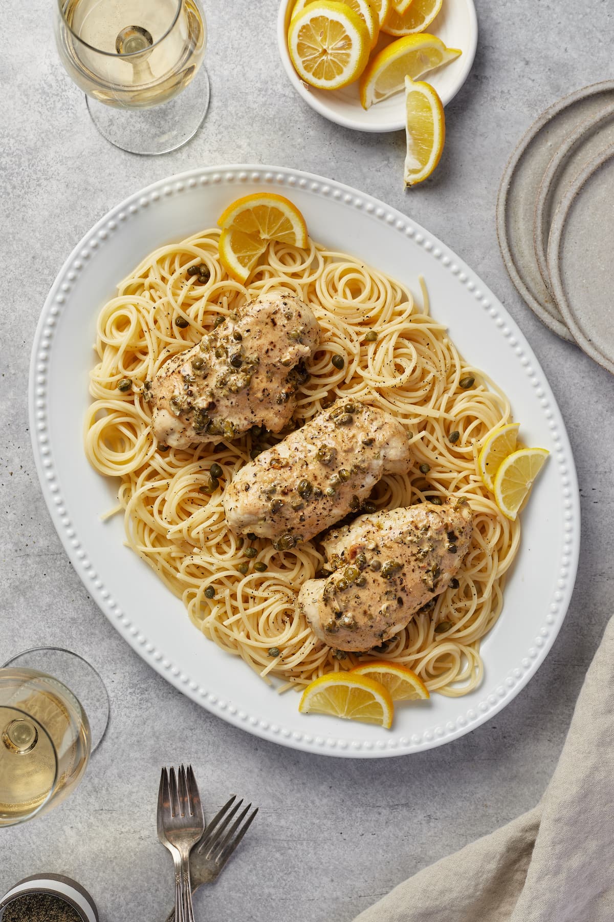 Chicken piccata pieces in lemon sauce served over a bed of spaghetti pasta.