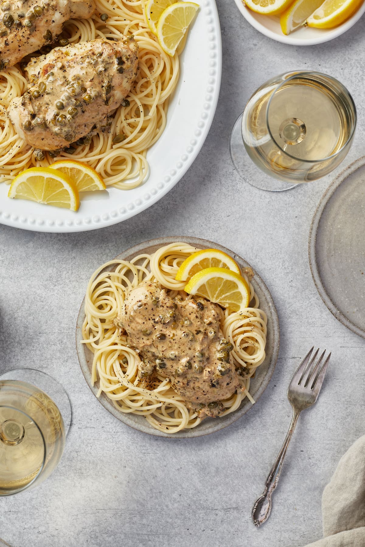 Chicken piccata served over pasta on a plate.