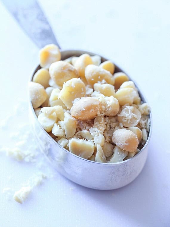 Macadamia nuts in a metal measuring cup.