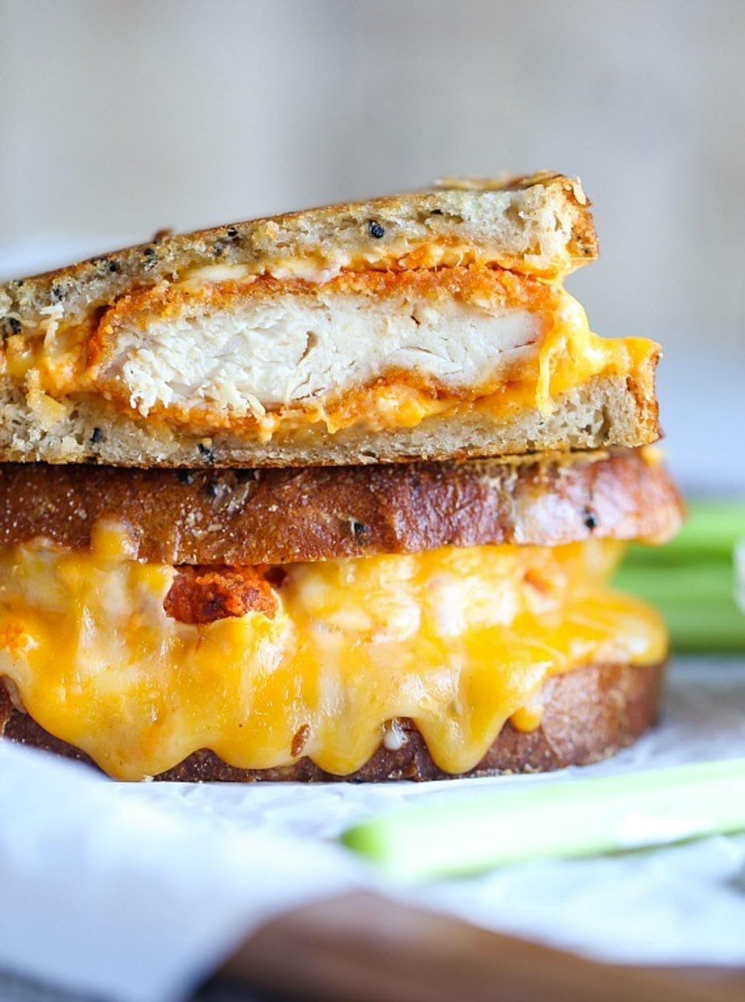 A buffalo chicken sandwich cut in half showing the inside of the chicken and melty cheese