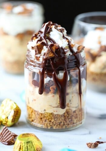 A no bake Butterfinger cheesecake cup loaded with Butterfinger candies and drizzled with chocolate sauce.