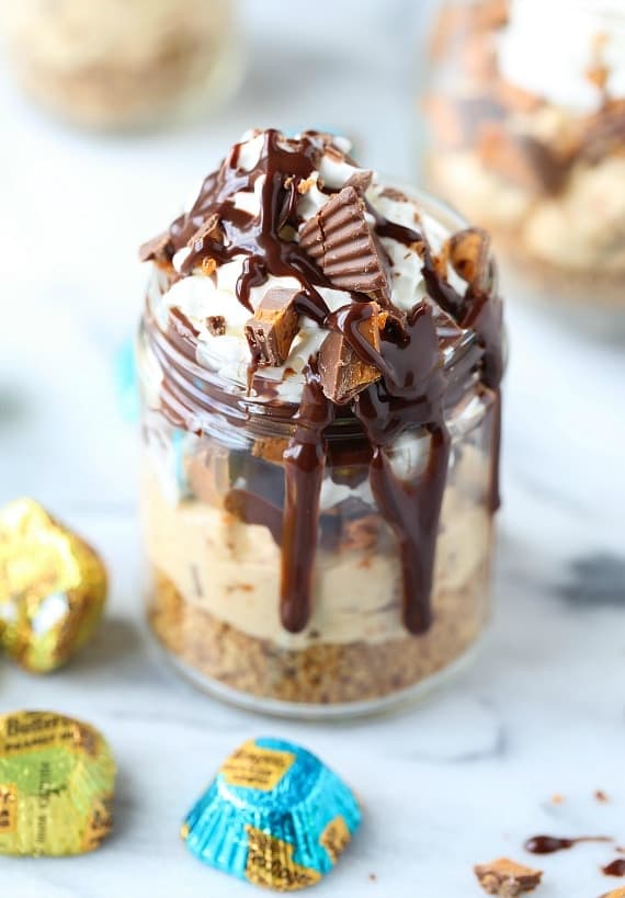 A no bake Butterfinger cheesecake cup loaded with Butterfinger candies and drizzled with chocolate sauce.