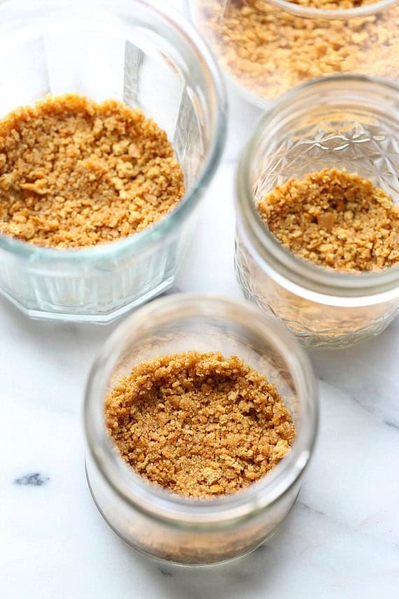 Three mason jars with a Graham cracker crust layer set in the bottoms.
