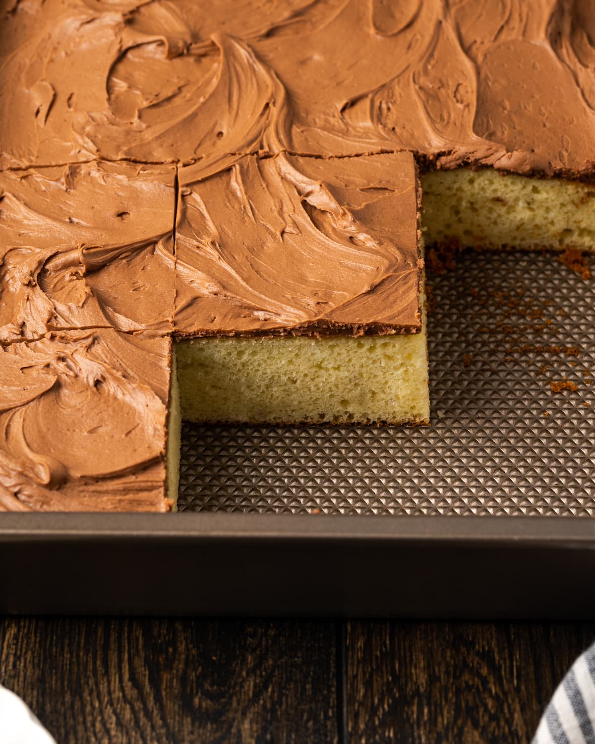 Sour cream cake in a baking pan with corner slices missing.