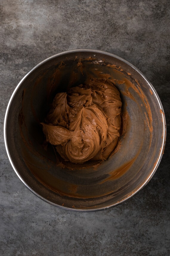 Chocolate frosting in a metal mixing bowl.