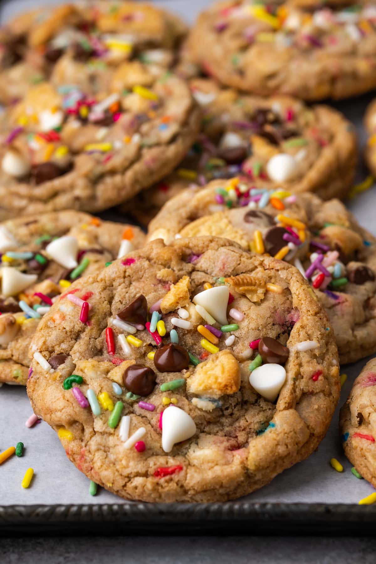 Assorted birthday cake chocolate chip cookies on top of a baking sheet lined with parchment paper.