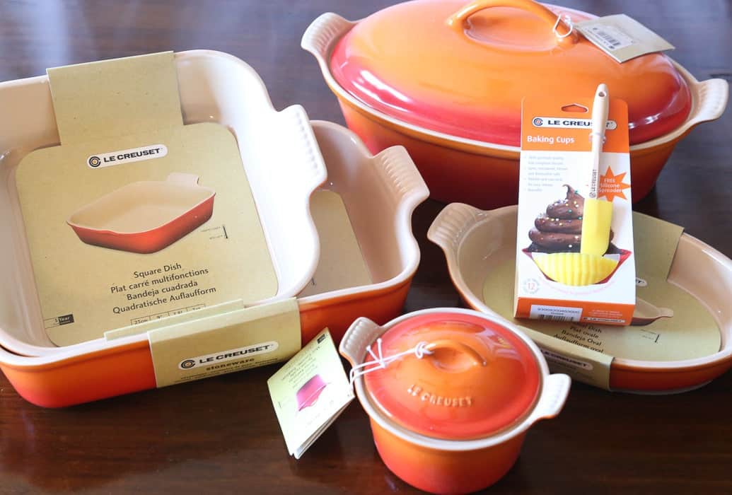 An Orange and Red Le Creuset Baking Set Arranged on a Wooden Table