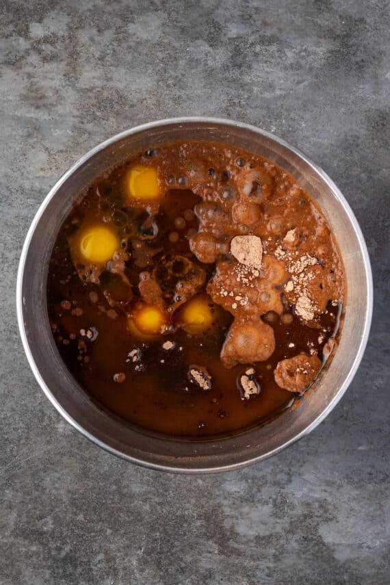 Chocolate cake batter ingredients combined in a metal mixing bowl.