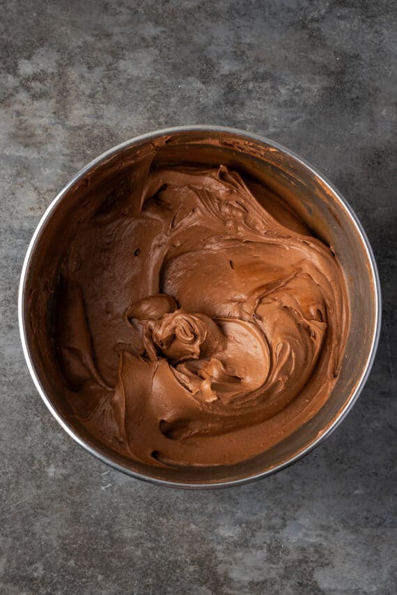 Fudge frosting in a metal mixing bowl.