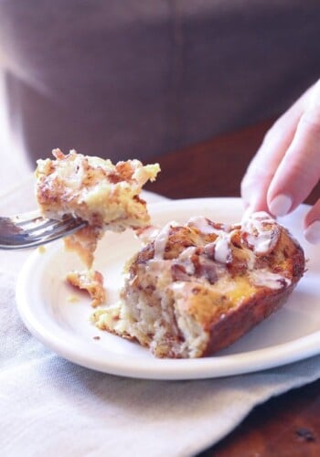 A serving of Cinnamon Roll Breakfast bake on a plate with a bite on a fork