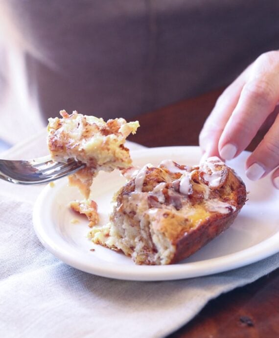 A serving of Cinnamon Roll Breakfast bake on a plate with a bite on a fork
