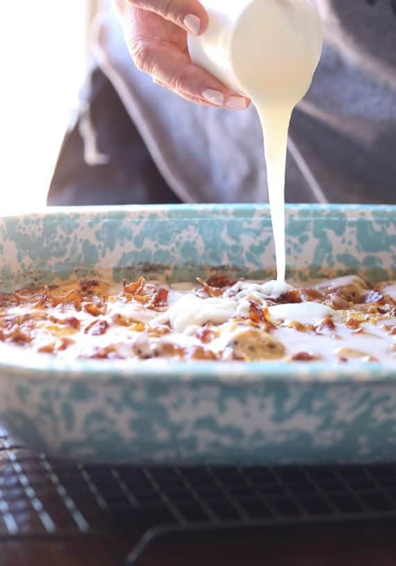 Icing being poured over Cinnamon Roll Breakfast Bake in a baking dish