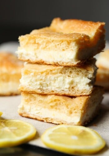 A stack of three lemon cream cheese bars surrounded by lemon slices.