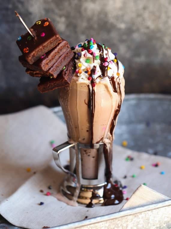 Rainbow Chip Brownie Milkshake in a glass with chocolate syrup.