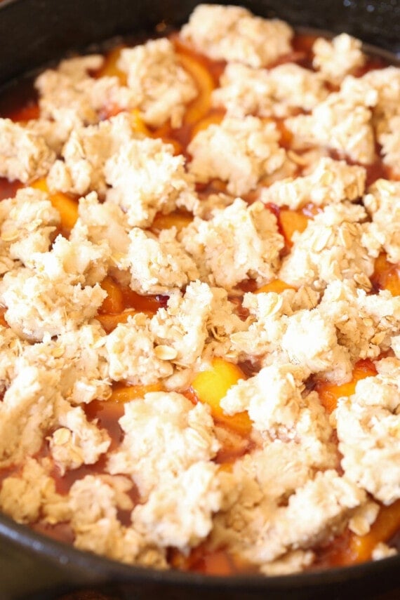 This easy skillet peach cobbler is made in one pan and topped with a chewy sugar cookie crumble. An easy, fun twist on a classic dessert! Peach cobbler topped with sugar cookie crumb topping