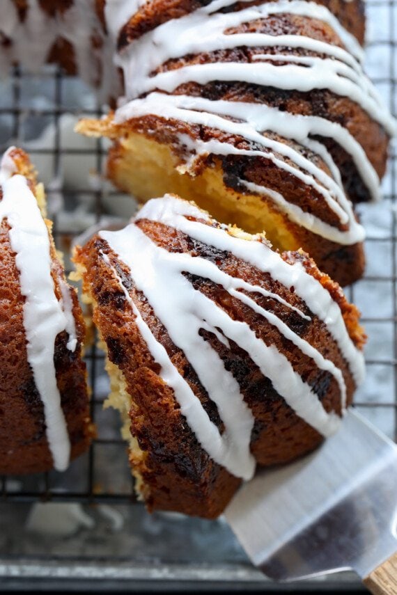 Slicing and serving vanilla bundt cake with a drizzle of white icing
