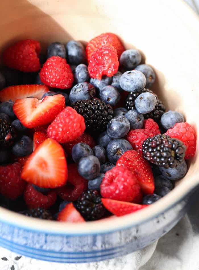 This light, airy angel food cake recipe is the perfect resting place for a juicy wine-soaked berry topping. An easy, elegant summer dessert! Fresh berries in a bowl.