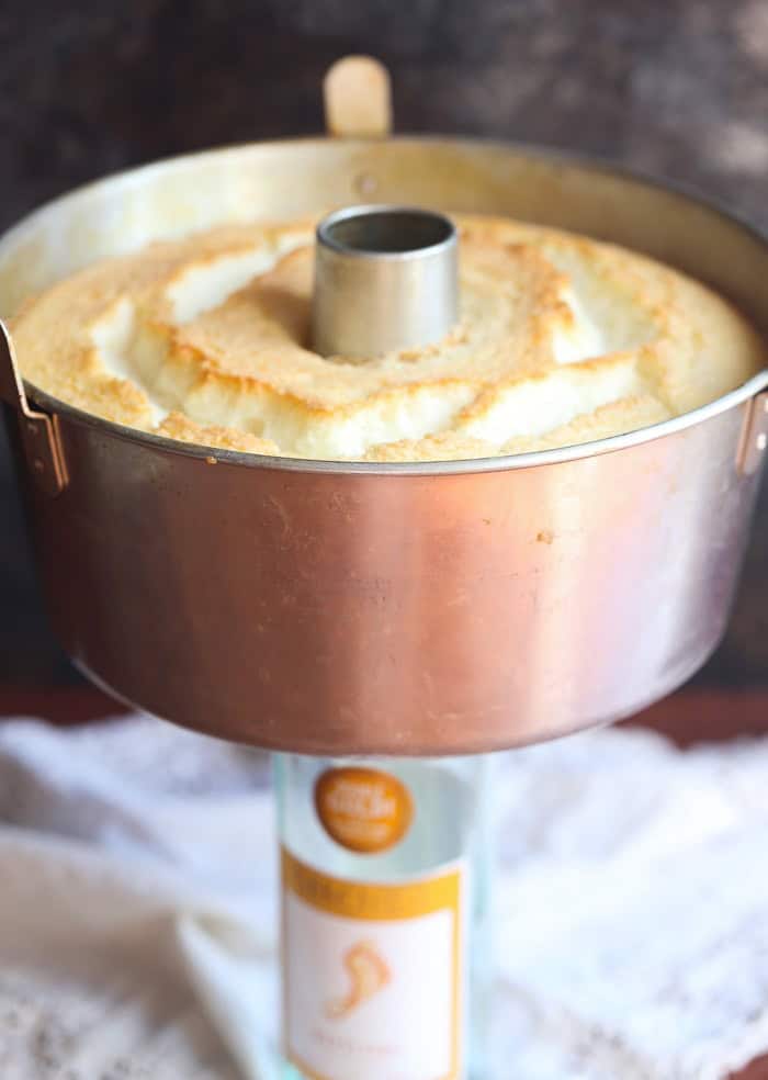 This light, airy angel food cake recipe is the perfect resting place for a juicy wine-soaked berry topping. An easy, elegant summer dessert! Golden-baked angel food cake inside a tube pan.