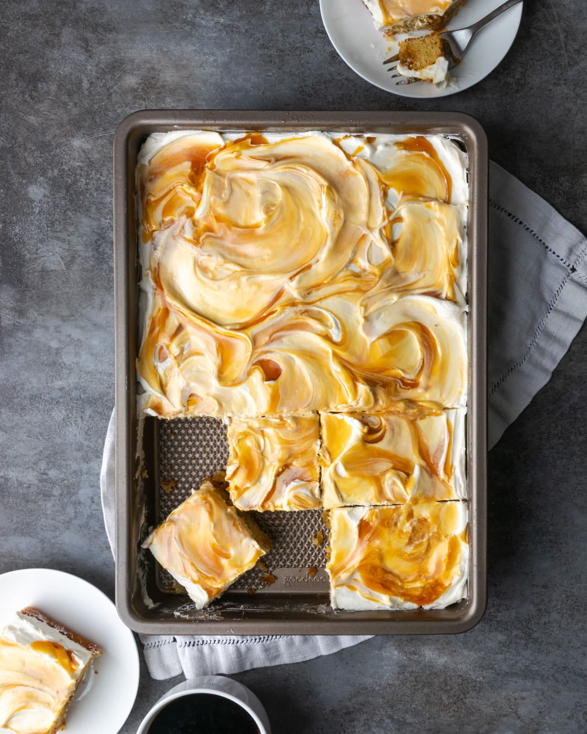 Top view of frosted caramel cake slices in a pan, with some pieces missing.