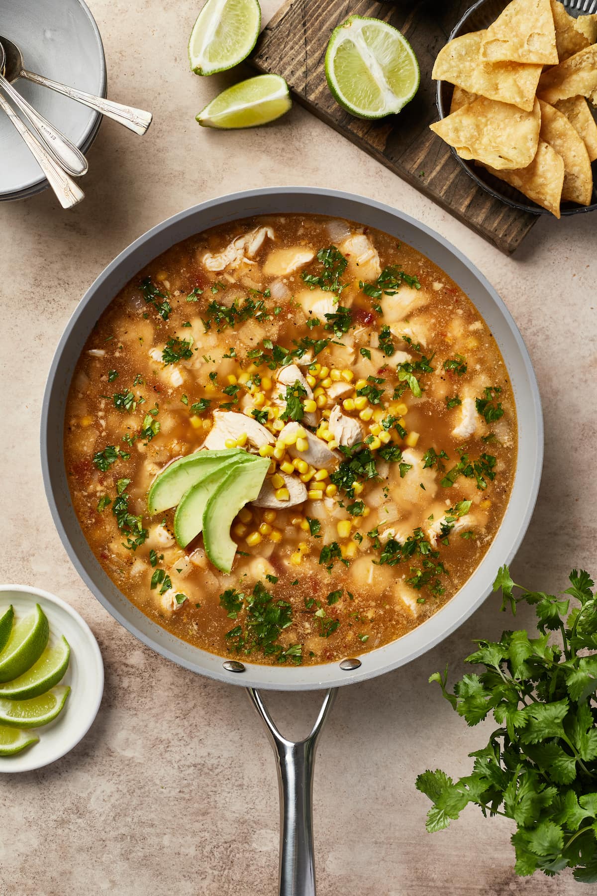 A pot of Mexican chicken soup garnished with avocado slices.