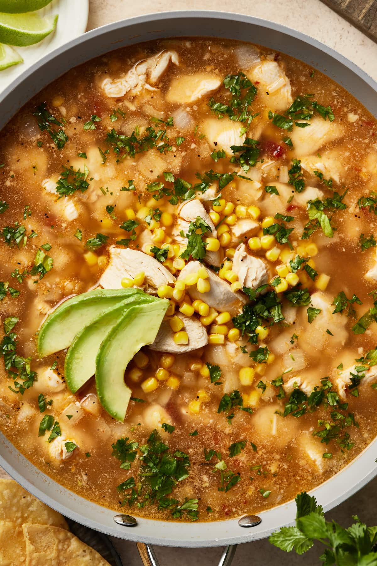 A pot of Mexican chipotle lime chicken soup garnished with avocado slices.