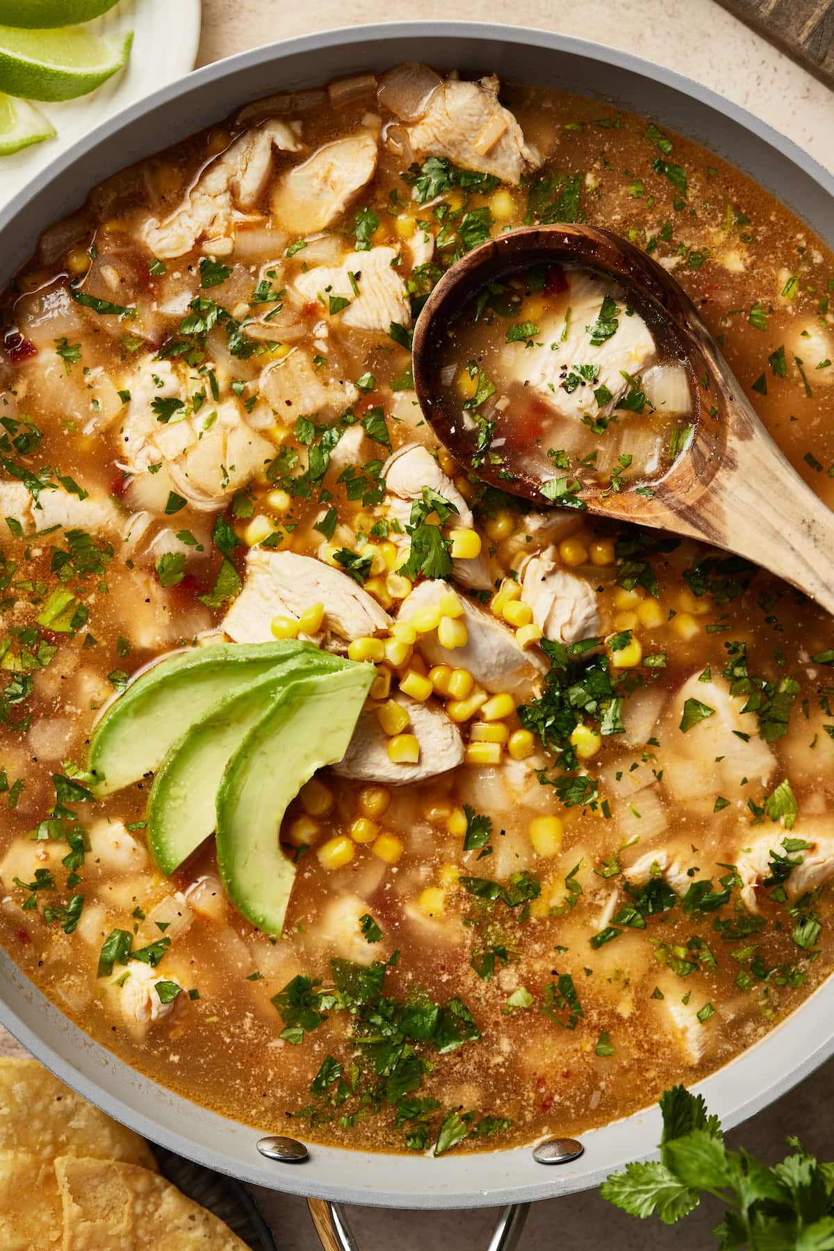 A pot of Mexican chipotle lime chicken soup garnished with avocado slices.