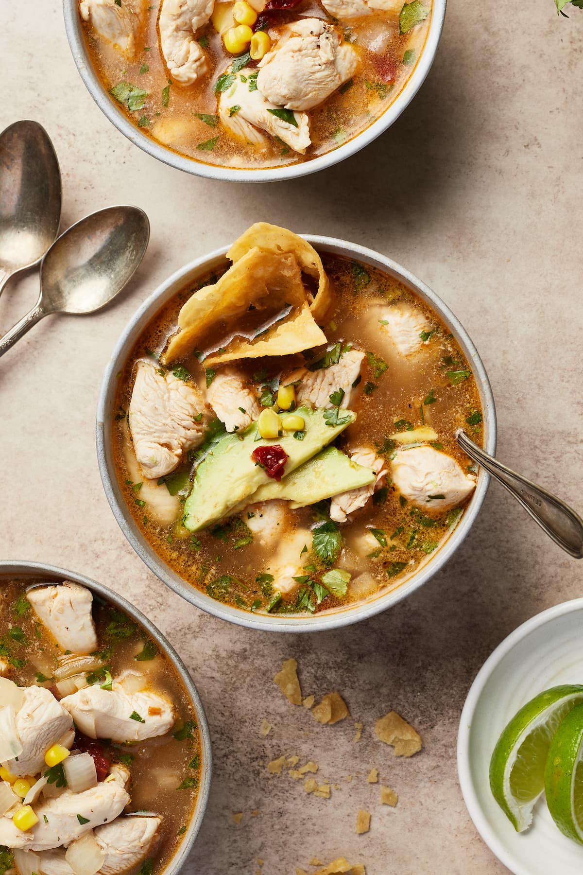 A bowl of Mexican chipotle lime chicken soup garnished with tortilla chips and avocado.