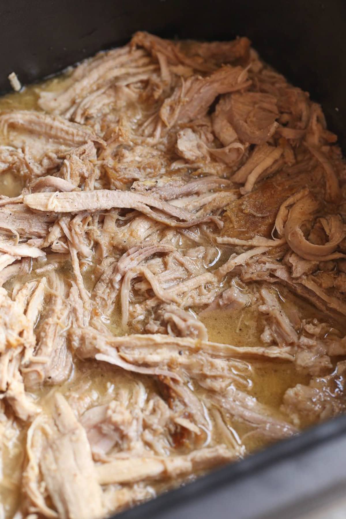 Cuban-style pulled pork in the bowl of a Crock Pot.