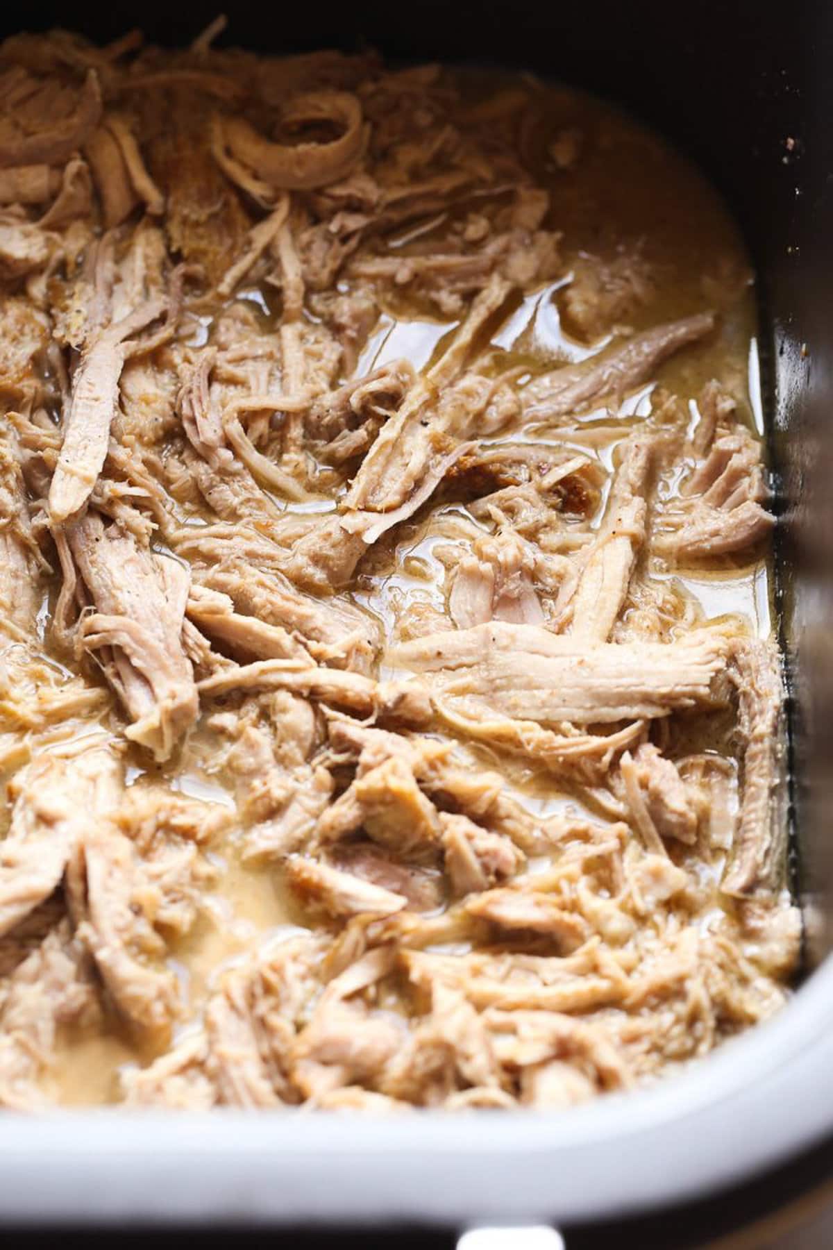 Cuban-style pulled pork in the bowl of a Crock Pot.