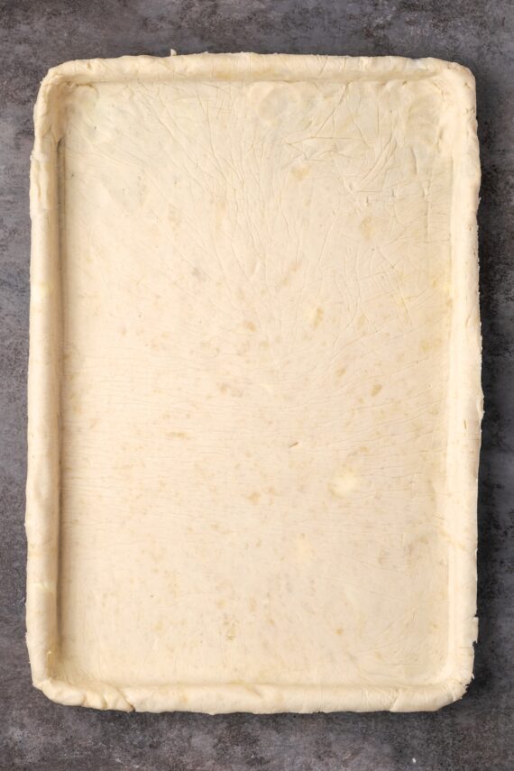 Pie crust rolled out inside a large rectangular pan.