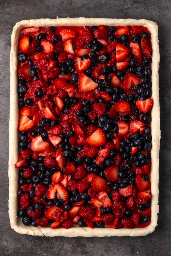 Berry filling added to the pie crust in a large rectangular baking pan.