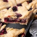 A slice of berry slab pie being lifted from the pan with a spatula.