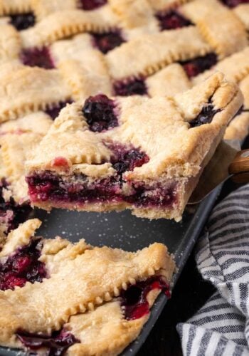 A slice of berry slab pie being lifted from the pan with a spatula.