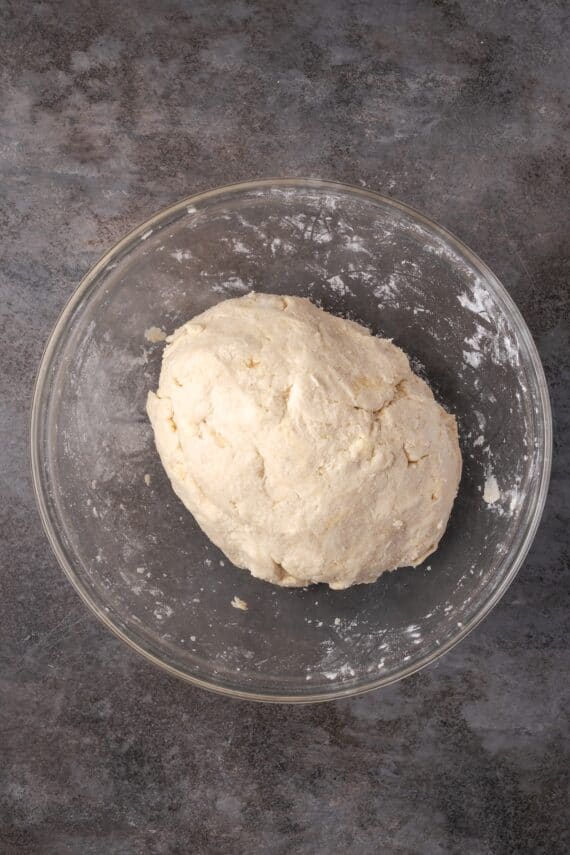 Pie dough shaped into a ball inside a glass bowl.