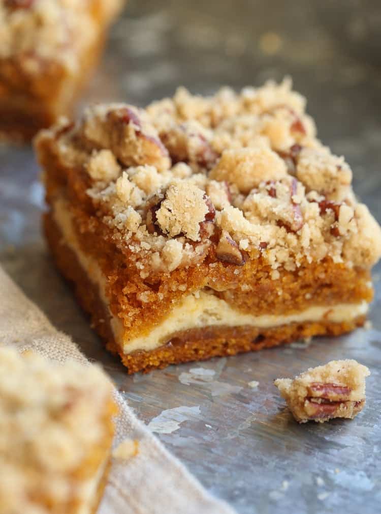 Close up of a pumpkin cheesecake bar topped with pecan praline.