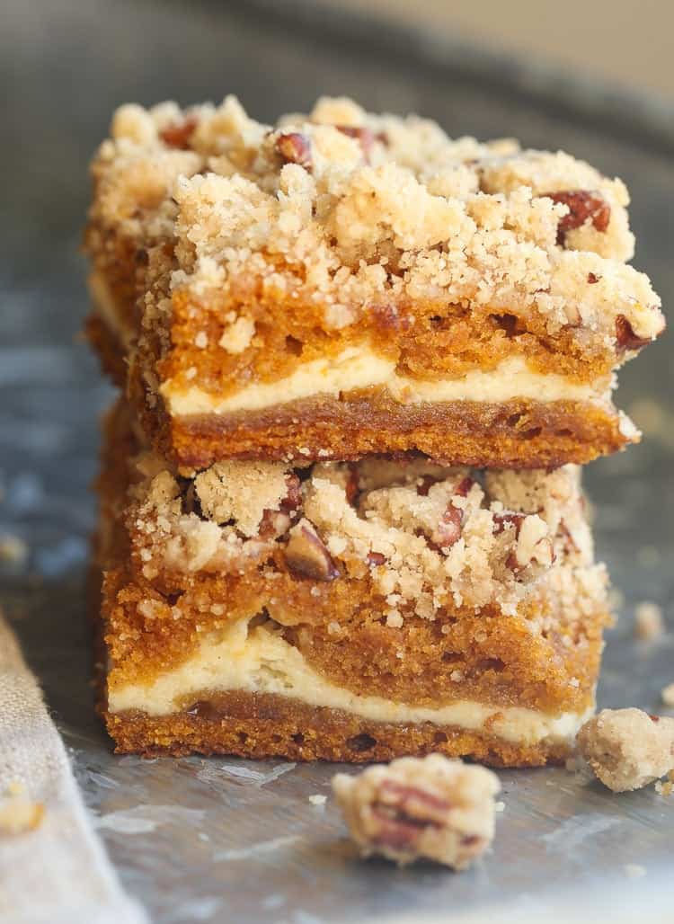 Two pumpkin cheesecake bars on top of each other, covered with a pecan praline. 