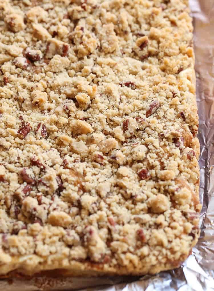 Overhead view of a baking dish full of uncut pumpkin cheesecake bars topped with a praline.