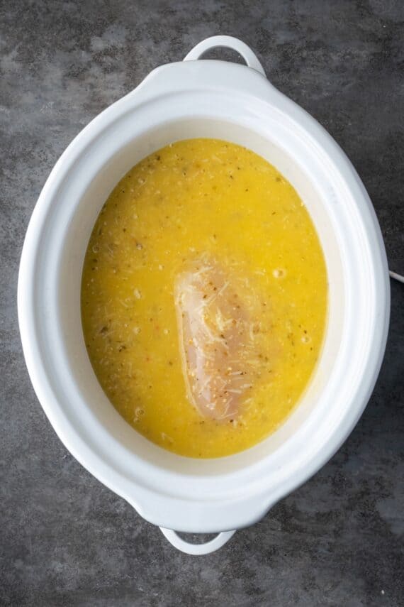 Chicken covered with Italian parmesan dressing inside the crock pot.